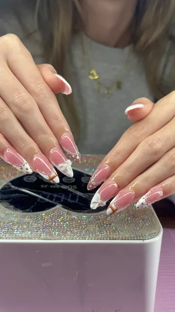 Long almond nails in sheer pink with white lace-edged French tips, white 3D bows and brown polka dots